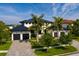 Beautiful two-story home with a black metal roof, white stucco, three-car garage and mature palm tree landscaping at 389 Bayview Ne Dr, St Petersburg, FL 33704