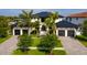 Beautiful two-story home with a black metal roof, white stucco, three-car garage and mature palm tree landscaping at 389 Bayview Ne Dr, St Petersburg, FL 33704
