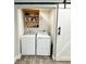Well-lit laundry area with white washer and dryer, storage shelves, and a sliding barn door at 428 45Th N Ave, St Petersburg, FL 33703