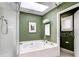 Bathroom featuring a large bathtub, green walls, and a window for natural lighting at 502 Palm Dr, Largo, FL 33770