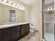 Bathroom with dual sinks, dark wood cabinets, a walk-in shower and tiled floors at 5022 Chipotle Ln, Wesley Chapel, FL 33544