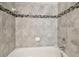 Close-up of a bathtub with elegant tiling and modern fixtures, and a decorative band at 5022 Chipotle Ln, Wesley Chapel, FL 33544