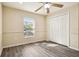 Bright bedroom with wood-look flooring, ceiling fan, closet doors, and a large window for natural light at 5022 Chipotle Ln, Wesley Chapel, FL 33544
