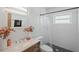 Modern bathroom with white tiled walls, marble vanity, window, and shower with transparent curtain at 5246 81 N St # 24, St Petersburg, FL 33709