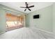 This bedroom features a ceiling fan, exterior view to a patio, and a wall-mounted television at 5428 Larchmont N Ct # 5428, Pinellas Park, FL 33782