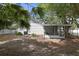 Exterior view of the home with manicured landscaping, mature trees and screened-in porch at 559 Scotland St, Dunedin, FL 34698