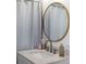 Bathroom featuring a modern vanity with marble countertop, round mirror, and decorative shower curtain at 559 Scotland St, Dunedin, FL 34698