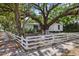 Quaint home featuring a white picket fence, mature trees, and a shaded outdoor seating area at 559 Scotland St, Dunedin, FL 34698