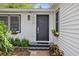 Charming home entrance with decorative tile, vibrant flowers, and a modern black door at 559 Scotland St, Dunedin, FL 34698