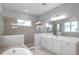 A modern bathroom features a soaking tub, glass shower, double sinks, and ample natural light at 6023 Cat Claw Ln, Bradenton, FL 34210