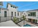 Modern white exterior featuring a balcony overlooking a pool and tropical landscaping at 6023 Cat Claw Ln, Bradenton, FL 34210