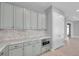 Close up of the kitchen area with grey cabinets, stone countertops, backsplash, and stainless steel microwave at 6023 Cat Claw Ln, Bradenton, FL 34210