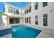 Luxury pool with travertine tile, a waterfall feature and modern architecture at 6023 Cat Claw Ln, Bradenton, FL 34210