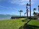 Beautiful waterfront view featuring manicured lawn, palm trees, an American flag, and a bridge on a sunny day at 6277 Bahia Del Mar Blvd # 110, St Petersburg, FL 33715