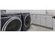 Well-lit laundry room with front load washer and dryer, shaker cabinets, quartz countertops and tile floors at 803 W Woodlawn Ave, Tampa, FL 33603