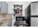 Kitchen area features stainless steel microwave, open shelving, mosaic backsplash, and stainless steel refrigerator at 1000 79Th N Ave # 211, St Petersburg, FL 33702