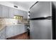 Charming kitchen with ample storage in grey cabinets, mosaic backsplash, and stainless steel refrigerator at 1000 79Th N Ave # 211, St Petersburg, FL 33702