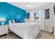Stylish bedroom featuring a bold blue accent wall, comfortable queen bed, and ample natural light at 10074 Bahama Ct, Seminole, FL 33776