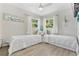 Bright bedroom featuring two twin beds, wood floors, and natural light from two windows at 10074 Bahama Ct, Seminole, FL 33776