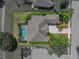 Aerial view of a home with a screened-in pool, a driveway, and a manicured lawn at 13538 Thoroughbred Dr, Dade City, FL 33525