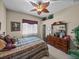 Comfortable bedroom with ceiling fan, large window, decorative art and a wood dresser at 13538 Thoroughbred Dr, Dade City, FL 33525