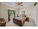 Cozy bedroom with neutral walls, ceiling fan, dark wood furniture, and a large window at 13538 Thoroughbred Dr, Dade City, FL 33525