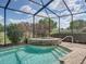 Screened-in pool with a stone-clad hot tub, offering a relaxing outdoor space at 13538 Thoroughbred Dr, Dade City, FL 33525