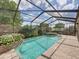 Inviting screened-in pool area featuring a waterfall and lush landscaping at 13538 Thoroughbred Dr, Dade City, FL 33525