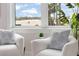 Close up of sitting area with chairs and large window view of the nearby beach and American flag at 187 145Th E Ave # 4, St Petersburg, FL 33708