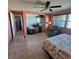 Well-lit bedroom with a floral bedspread, tile floors, and a view into the hall at 2110 Society Dr, Holiday, FL 34691