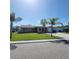 Charming single-story home with a well-maintained lawn, palm trees, and a driveway leading to an attached garage at 2110 Society Dr, Holiday, FL 34691