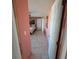 Hallway with salmon-colored walls and tile flooring leading to a bright bedroom at 2110 Society Dr, Holiday, FL 34691