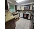 Cozy kitchen featuring white cabinets and tile floors, equipped with essential appliances at 2110 Society Dr, Holiday, FL 34691
