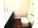 Standard bathroom with a dark wood floor, a toilet, and a sink with a dark blue cabinet at 2302 Maki Rd # 24, Plant City, FL 33563