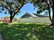 Well-manicured lawn and mature trees frame the house with a white fence at 3000 Tangerine Ter, Palm Harbor, FL 34684