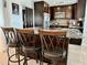Gourmet kitchen featuring an island with granite countertops, dark cabinets, and stainless steel appliances at 3000 Tangerine Ter, Palm Harbor, FL 34684