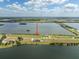Aerial view of a home situated between two bodies of water, featuring a pool under a partly cloudy sky at 3409 Gulf City Rd, Ruskin, FL 33570