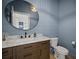 Charming powder room featuring wood-look vanity with marble counters and blue accent wall at 3409 Gulf City Rd, Ruskin, FL 33570
