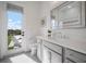 Bright bathroom with gray cabinets, quartz counters, and door to backyard with lounge chairs at 3409 Gulf City Rd, Ruskin, FL 33570