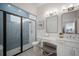 Modern bathroom features a glass-enclosed shower, vanity with double mirrors and soft gray accent tiles at 3409 Gulf City Rd, Ruskin, FL 33570