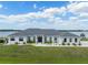 Stunning lakefront home with lush green lawn, elegant landscaping, and a classic white facade under a sunny sky at 3409 Gulf City Rd, Ruskin, FL 33570