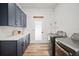 This modern laundry room features sleek stainless steel appliances, counter space, and navy blue storage cabinets at 3409 Gulf City Rd, Ruskin, FL 33570