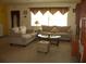 Comfortable living room featuring neutral-toned sofas, a glass-top coffee table, and large window at 4179 Juniper St, Port Charlotte, FL 33948