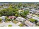 Aerial view of the single-story home, pool, and surrounding neighborhood with lakes and mature trees at 4240 Woodsville Dr, New Port Richey, FL 34652