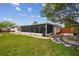 Wide shot of the grassy backyard with a view of the enclosed patio and a wooden fence at 4240 Woodsville Dr, New Port Richey, FL 34652