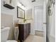 Well-lit bathroom featuring a toilet, a vanity with dark wood cabinets and decor, and a tiled floor at 4240 Woodsville Dr, New Port Richey, FL 34652