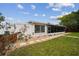 Back exterior showing green lawn, rocks, pavers, and a screened-in porch at 4240 Woodsville Dr, New Port Richey, FL 34652