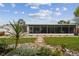 Back exterior with stone path, stepping stones, green lawn, and large screened-in porch at 4240 Woodsville Dr, New Port Richey, FL 34652