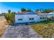 The exterior of a home with a simple design and an adjacent driveway on an overgrown lot at 500 79Th Ave, St Pete Beach, FL 33706