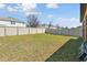 Backyard featuring a large grassy area with a white fence and privacy bushes at 5147 Brickwood Rise Dr, Wimauma, FL 33598